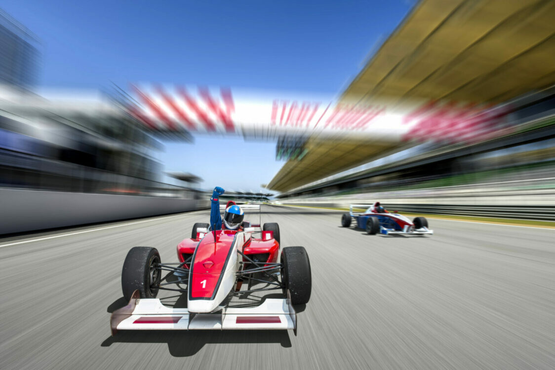 A racing car in focus as it zooms through the finish line, blurry behind it