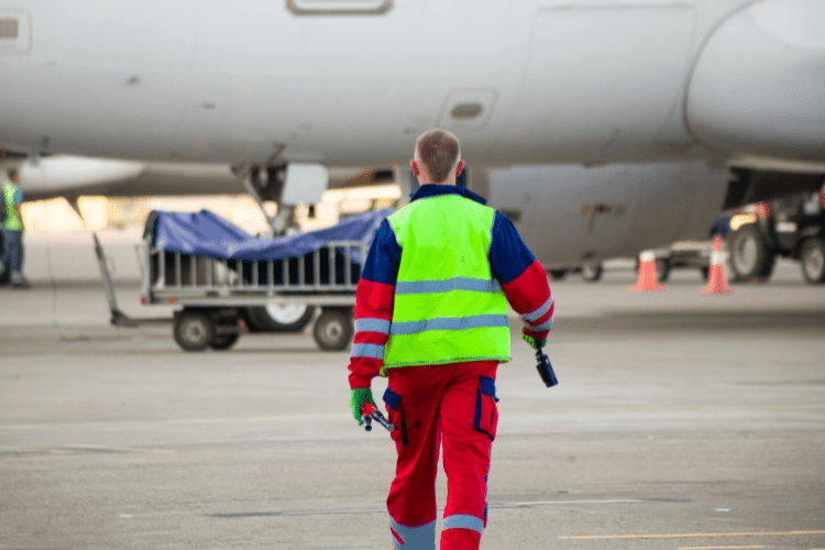 A ground handler wearing high-vis walking towards an aircraft
