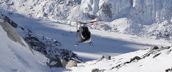 A helicopter flying over a snowy mountain landscape