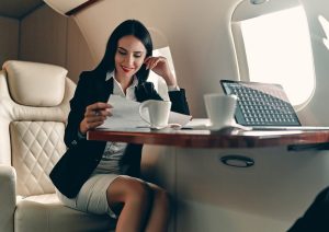Woman sitting in pivate jet, while working and drinking coffee